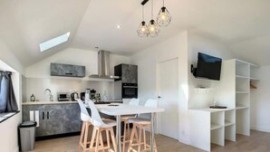 A modern kitchen with a dining area, built-in appliances, and a TV mounted on the wall.