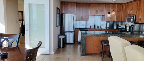 A modern kitchen with wooden cabinets, stainless steel appliances, and a granite countertop.