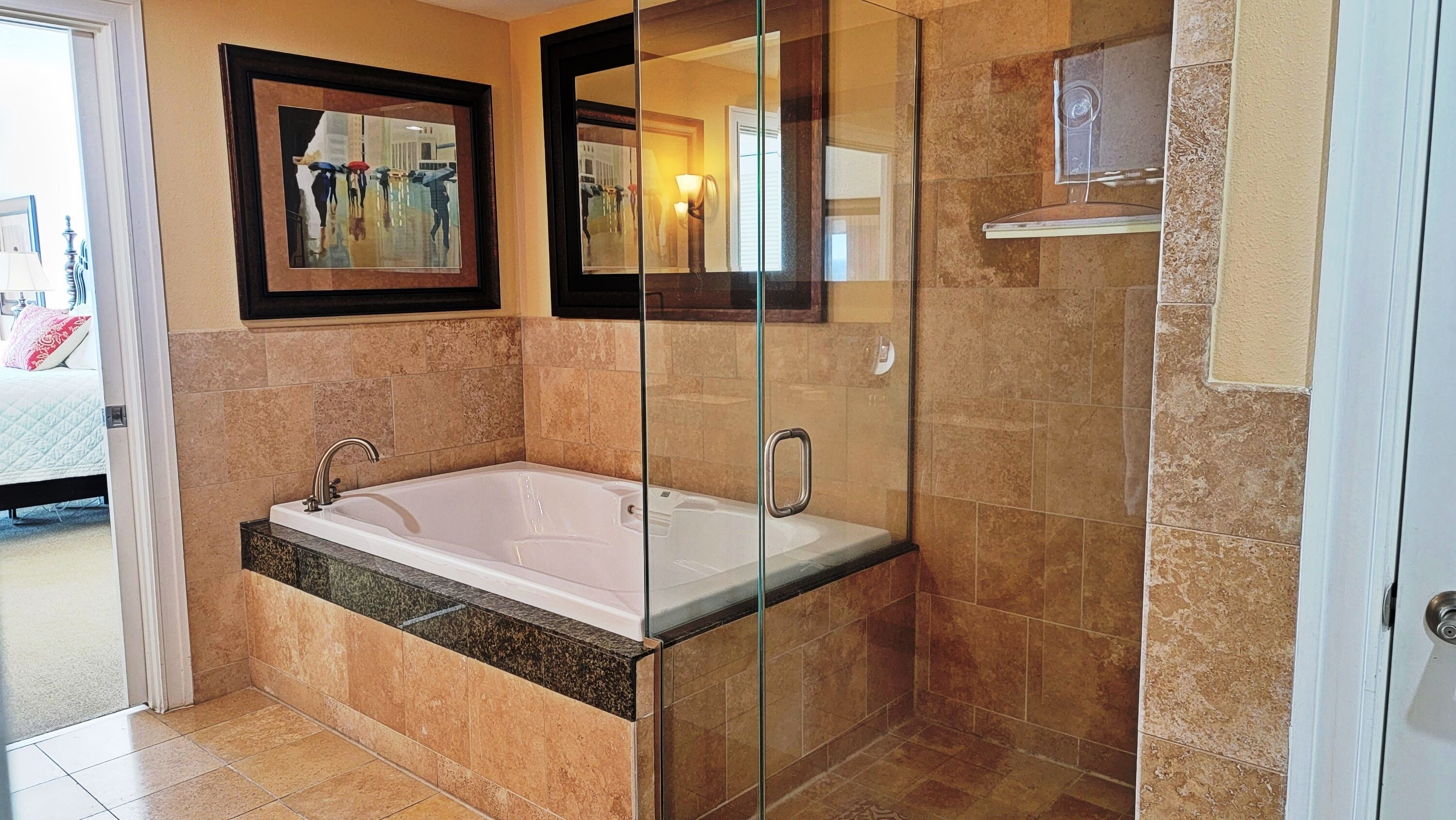 Een moderne badkamer met een glazen douchecabine, een vrijstaand bad en een lijstwerkkunstwerk aan de muur.