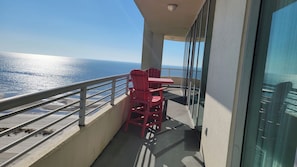 Un balcon avec une table et deux chaises, donnant sur une étendue d’eau.