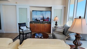 A modern living room with a sofa, armchairs, a coffee table, and a TV displaying various streaming services. - Ocean Club 805 Deluxe | Stunning Panoramic Views of the Gulf! (Biloxi)