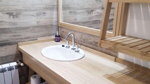 A modern bathroom with a wooden vanity, a white sink, and a mirror.
