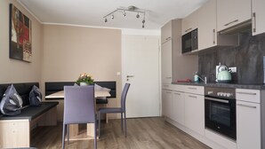 Una cocina moderna con microondas, horno y hervidor. Hay un comedor con mesa y sillas.
