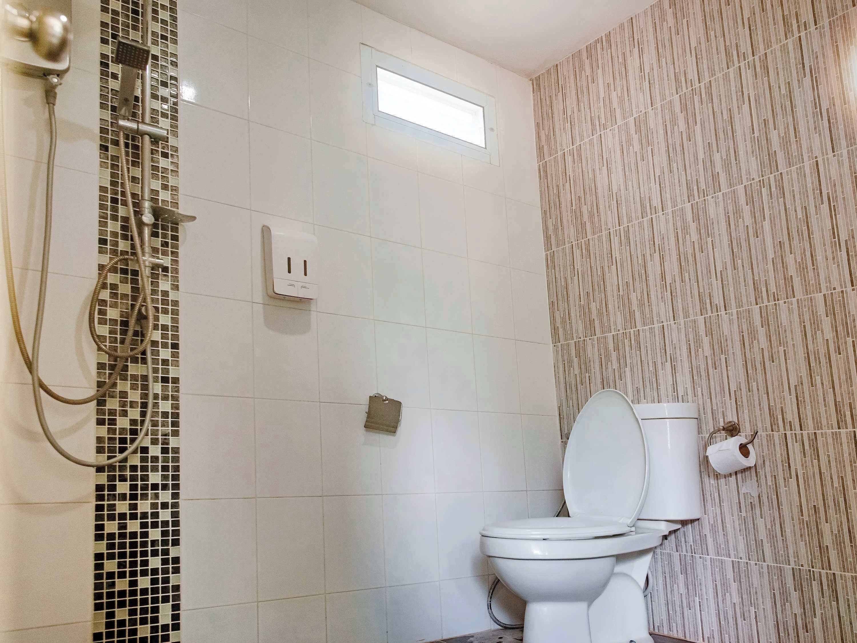 Un baño con inodoro, ducha y un aplique de pared.