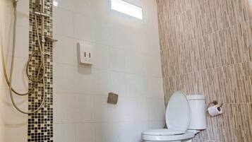 Un baño con inodoro, ducha y un aplique de pared.