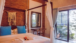 Un dormitorio con una cama con dosel, un colgador de macramé, un espejo y vistas al exterior.