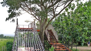 Un puente colgante y una escalera de madera en un exuberante jardín.