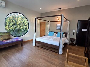 A four-poster canopy bed with a view of greenery through a large circular window. - Tantai Eco Farm Stay at Khao Yai (Pak Chong)