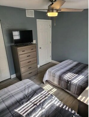 A bedroom with two beds, a dresser, a television, and a ceiling fan. - Legoland 3 Bedroom Pet Friendly Pool Home (Winter Haven)