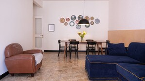 Zona de menjador amb taula, cadires, sofà i una paret decorativa.