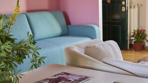Une pièce avec un canapé bleu, un fauteuil blanc et une table sur laquelle se trouve un magazine.