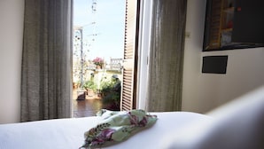 Une chambre d’hôtel avec un lit, des rideaux, une fenêtre et une vue sur le balcon extérieur.