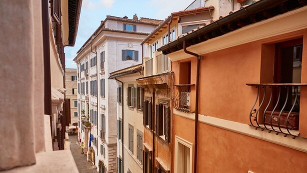 Une rue étroite, bordée de bâtiments des deux côtés, avec des balcons et des fenêtres.