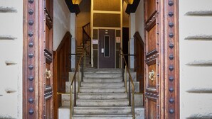 A staircase leading to a door with ornate metal studs and a brass handle.
