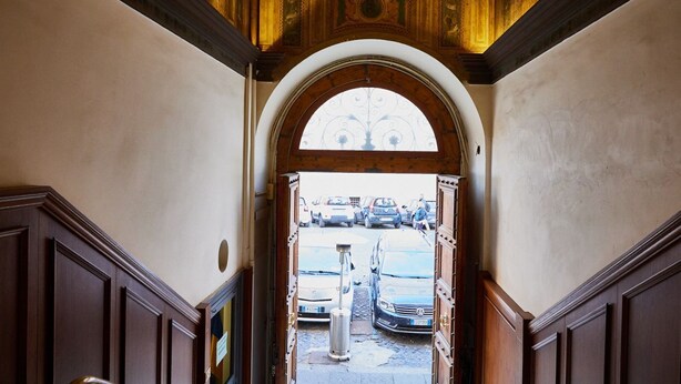 An arched doorway leading to a parking area with cars.