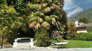 A swimming pool with a lounge chair, surrounded by lush greenery and a mountain backdrop.