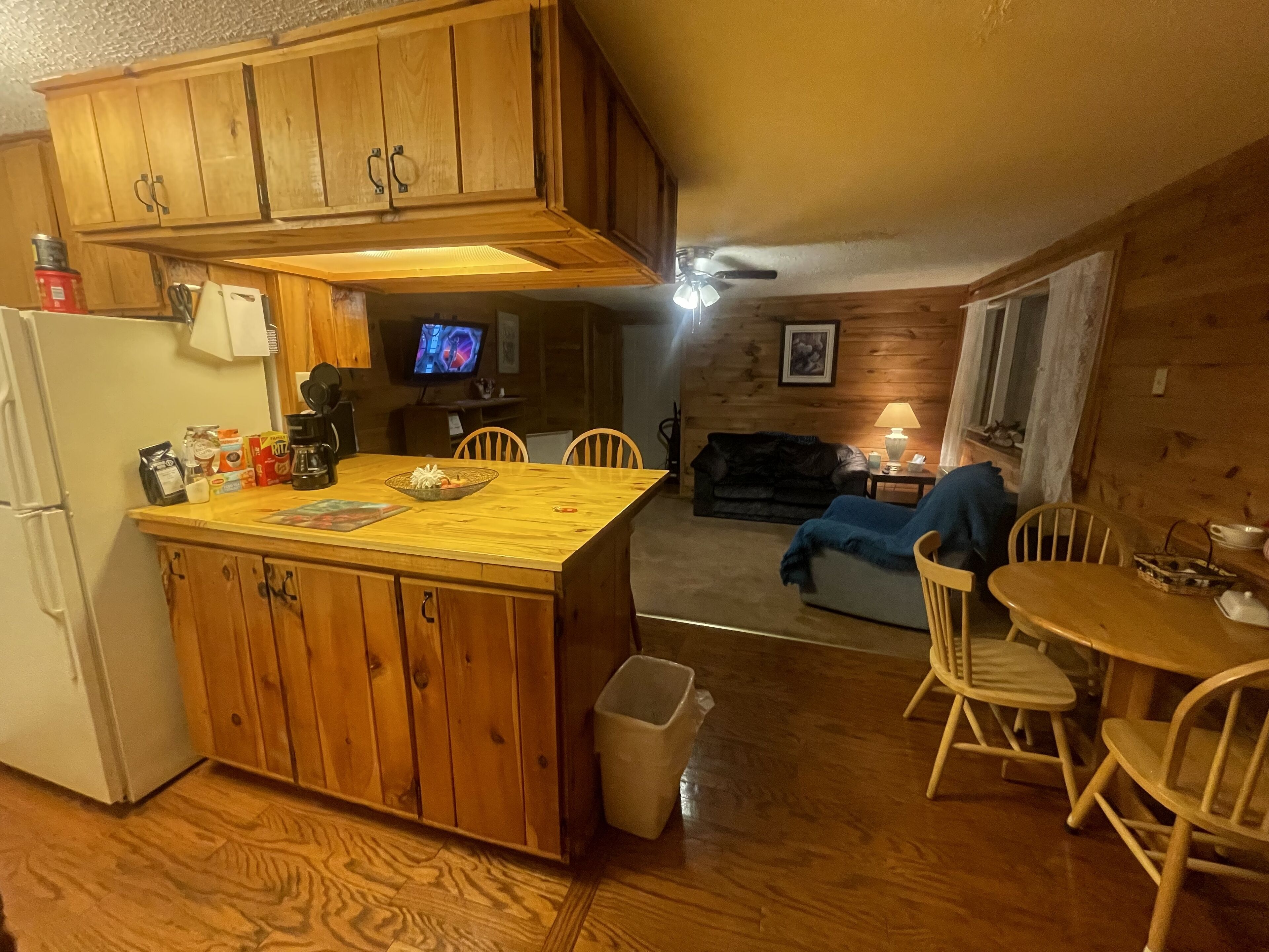 A kitchen with wooden cabinets, a refrigerator, and a dining area with a table and chairs.
