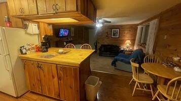 A kitchen with wooden cabinets, a refrigerator, and a dining area with a table and chairs.
