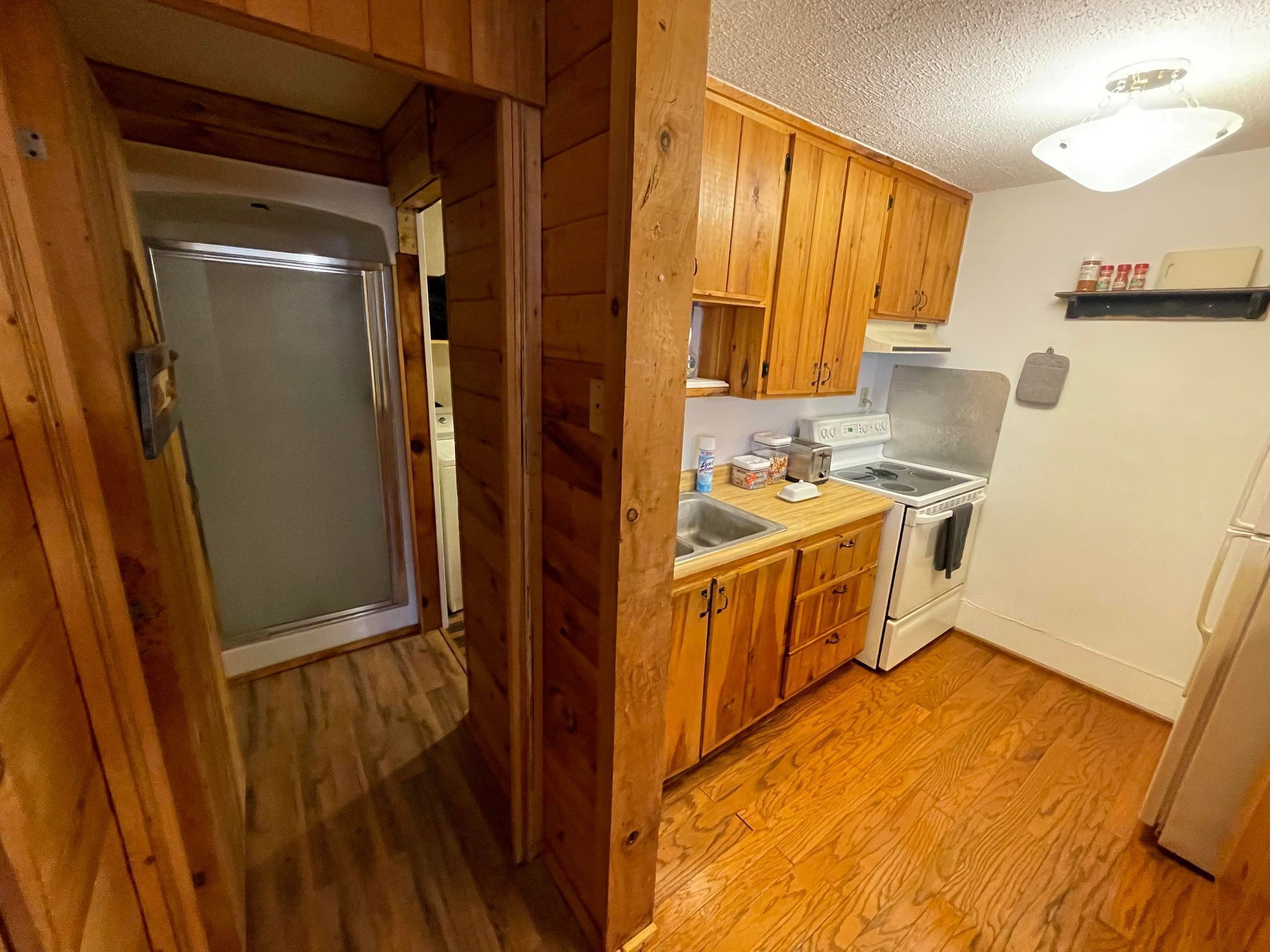 A compact kitchen with wooden cabinets, a sink, and a stove.