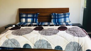 A bed with a wooden frame, blue and white patterned bedding, and a quilt with circular designs. - Gurugram Aravali Farmhouse  (Sohna)