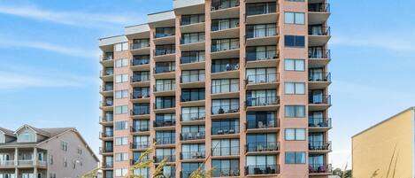A multi-story residential building with balconies, large windows, and a flat roof.