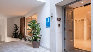 A hotel entrance with a potted plant, a blue sign, and a door leading inside. - Hommyhome Tetuán 15 Boutique - 103 (Sevilla)