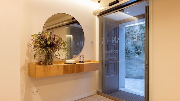 A modern interior with a wooden console, a round mirror, and a vase with flowers. - Hommyhome Tetuán 15 Boutique - 202 (Sevilla)
