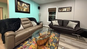 A modern living room with two leather sofas, a glass coffee table, and colorful abstract art on the walls. - Home away from home!!! (Sun Prairie)