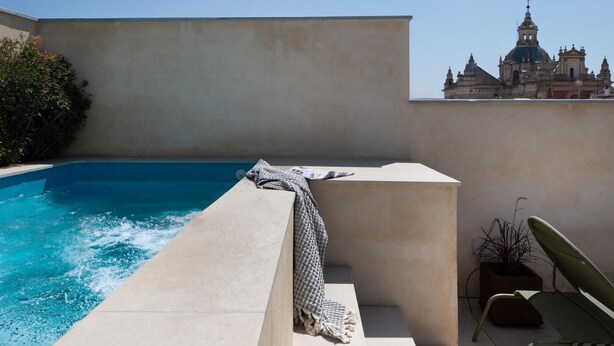 Un espace piscine aménagé sur le toit, offrant une vue sur un bâtiment historique en arrière-plan.
