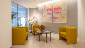 Un salon moderne avec des canapés jaunes, une table basse ronde et des œuvres d’art abstraites accrochées au mur.