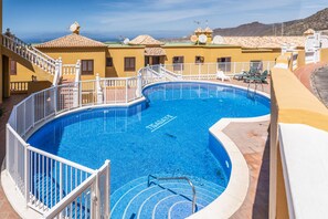Piscina com grade branca, escadas e vista para o mar.