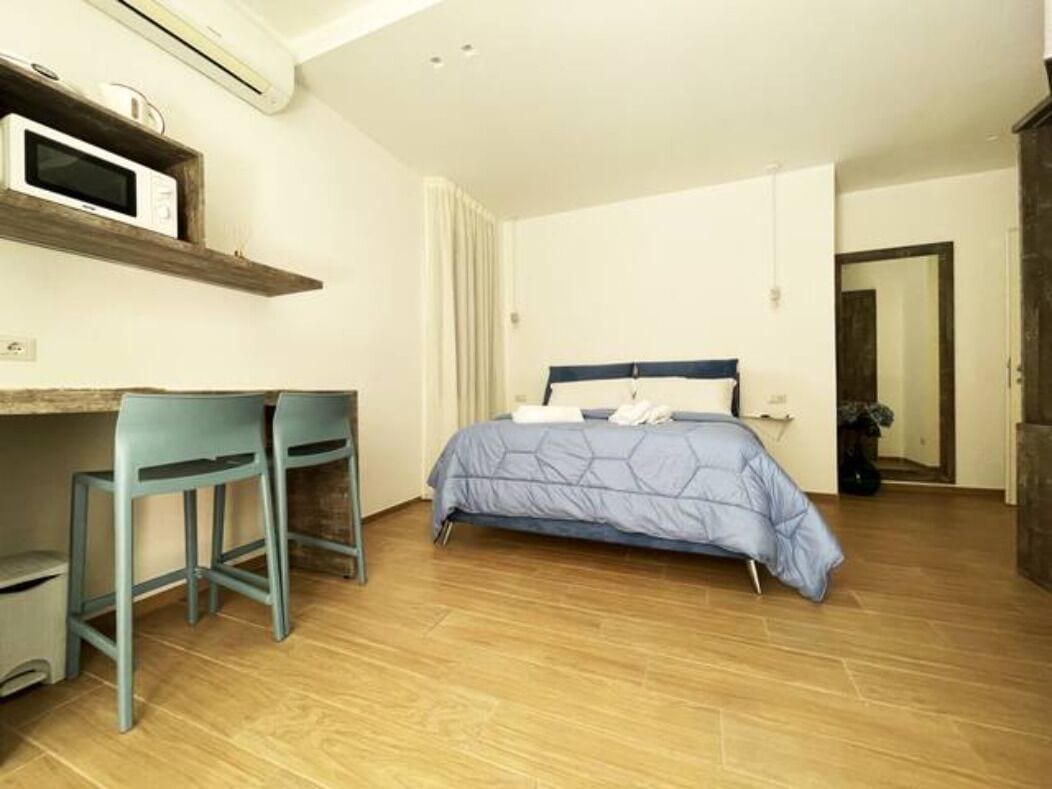 Ein Schlafzimmer mit einem Bett, einem Schreibtisch mit zwei Stühlen und einer Mikrowelle auf einem Regal.