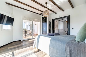 A bedroom with a large bed, wooden beams on the ceiling, a hanging light fixture, and a view of the outdoor patio. - Ref.126-Luxury Villa with Breathtaking Views in Mijas (Mijas)