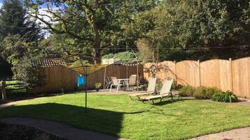 Relax in a serene backyard oasis with a hammock-style shade structure, lounge chairs, and a small table.