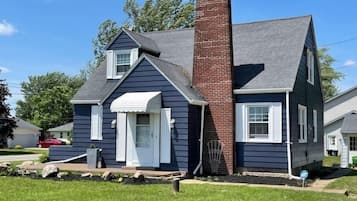 Stunning home with a brick chimney, front porch, and beautifully manicured lawn.