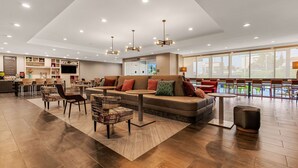 A spacious lobby with a modern sofa, chairs, and a coffee table. There are multiple ceiling lights and a large window offering a view of the outdoors. - Home2 Suites By Hilton Cookeville (Cookeville)
