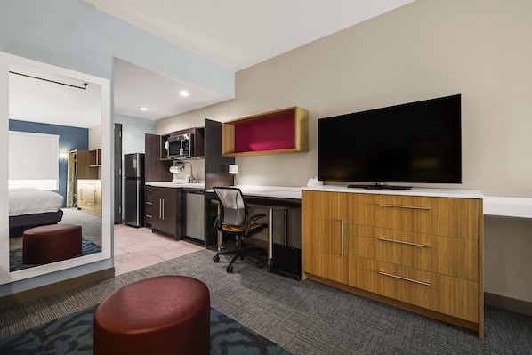 A hotel room with a bed, a desk, a TV, and a kitchenette. - Home2 Suites By Hilton Cookeville (Cookeville)