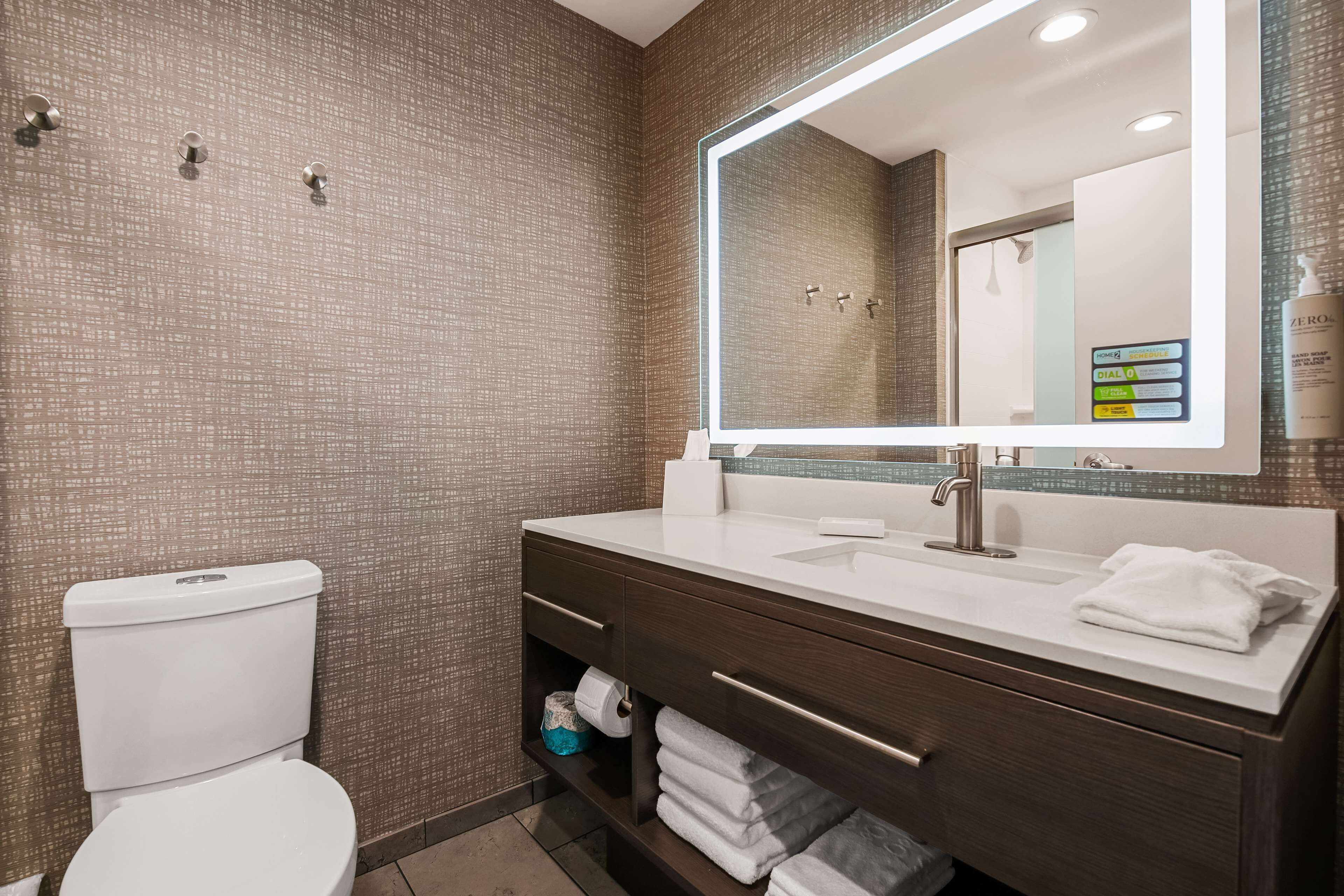 A modern bathroom with a toilet, a sink with a mirror, and a towel rack.
