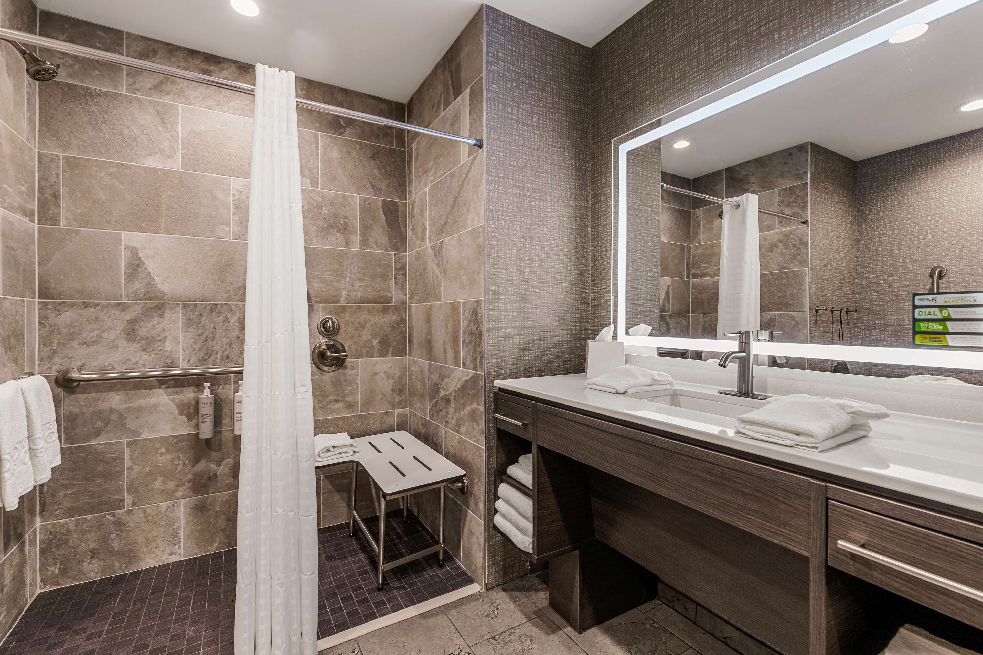A modern bathroom with a shower, a vanity with a mirror, and a towel rack.