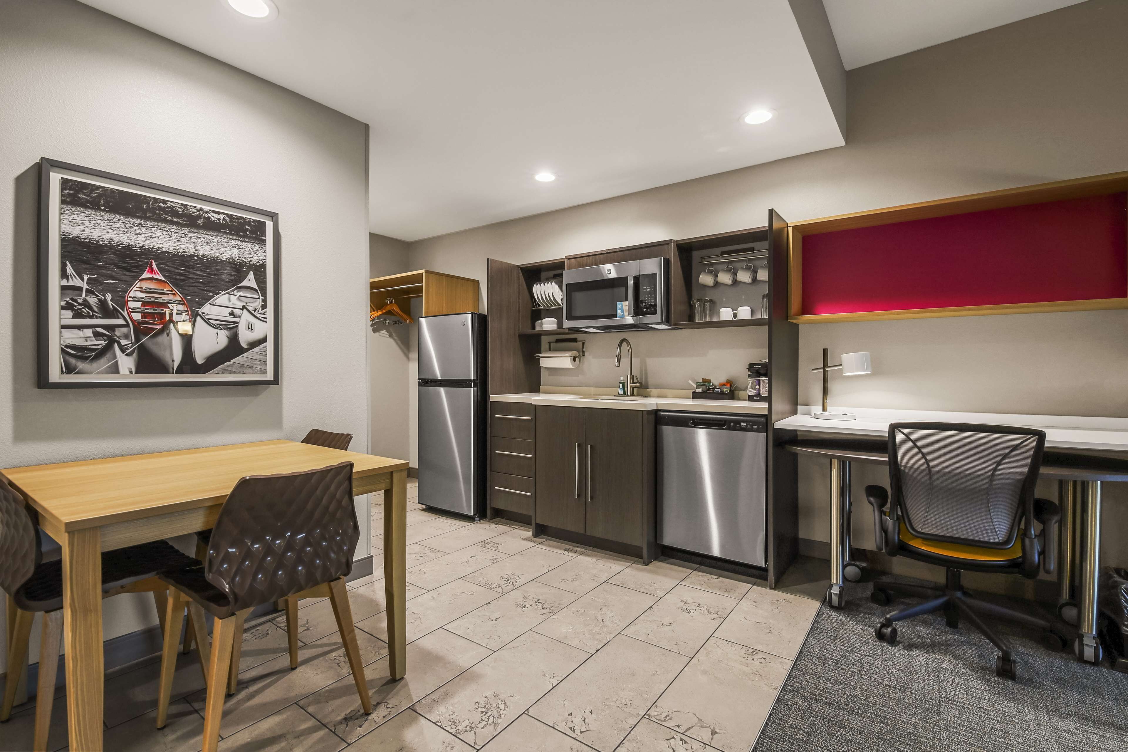 A modern kitchen with a dining area, stainless steel appliances, and a red accent wall.