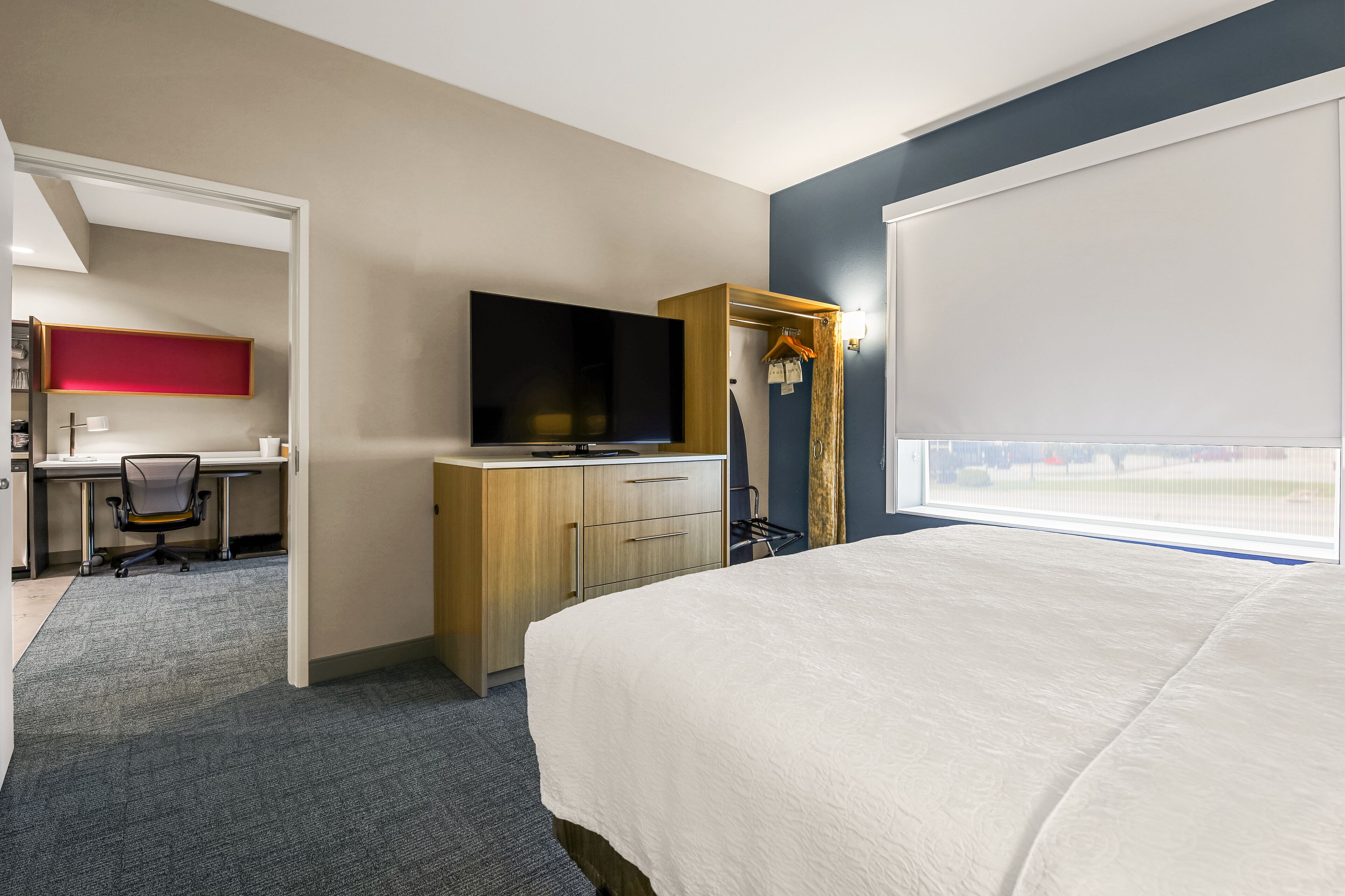 Una habitación de hotel con cama, escritorio, televisor y armario.
