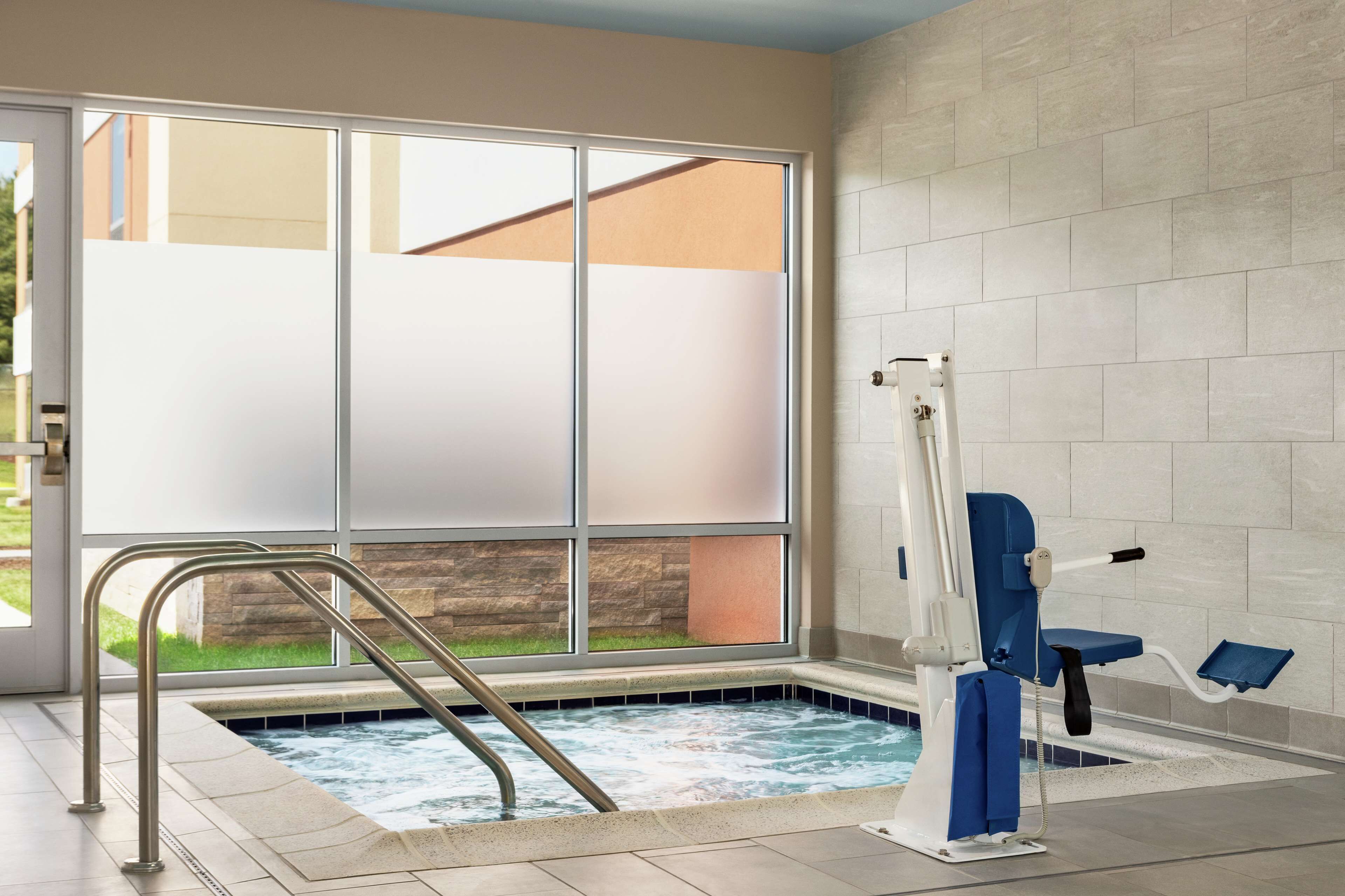 A spa area with a hot tub, a window with frosted glass, and a pool lift.