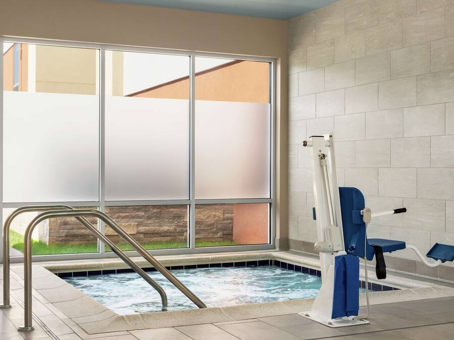 A spa area with a hot tub, a window with frosted glass, and a pool lift.