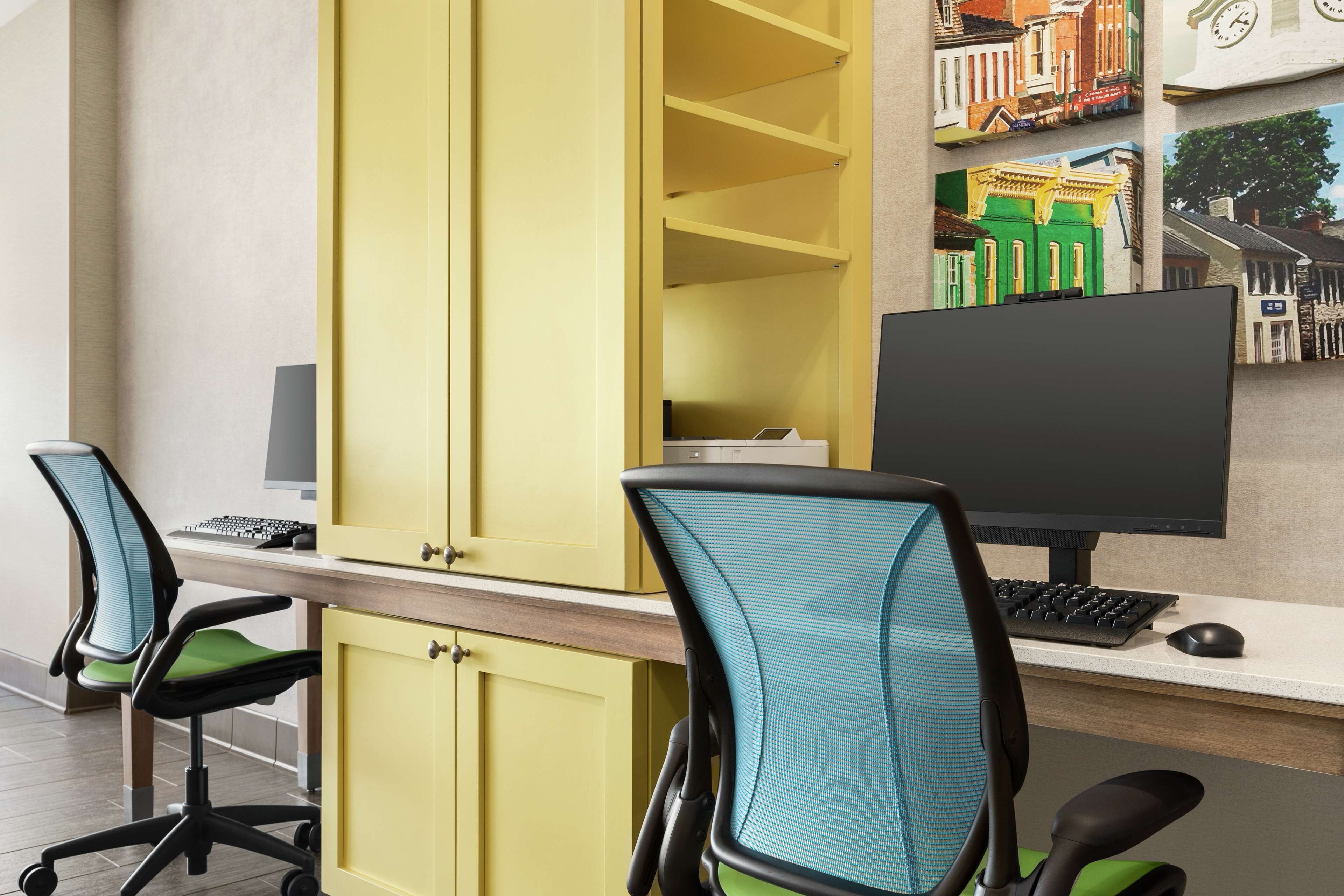 A workspace with two chairs, a desk, a computer, and a yellow cabinet.