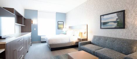 A hotel room with a bed, a sofa, a desk, and a television.