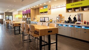 A modern cafe with multiple seating areas, a counter with food and drink options, and a 'Good Morning' sign. - Home2 Suites by Hilton Leesburg (Leesburg)