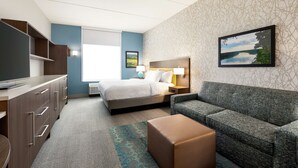 A hotel room with a bed, a sofa, a TV, a desk, and a window. - Home2 Suites by Hilton Leesburg (Leesburg)