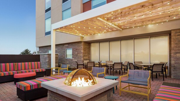 An outdoor patio with a fire pit, seating, and a covered area with string lights. - Home2 Suites by Hilton Leesburg (Leesburg)