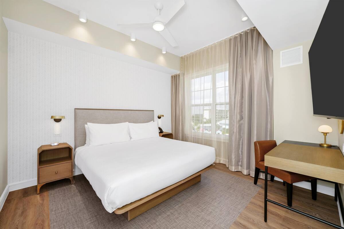 Een hotelkamer met een bed, nachtkastjes, een bureau en een stoel.