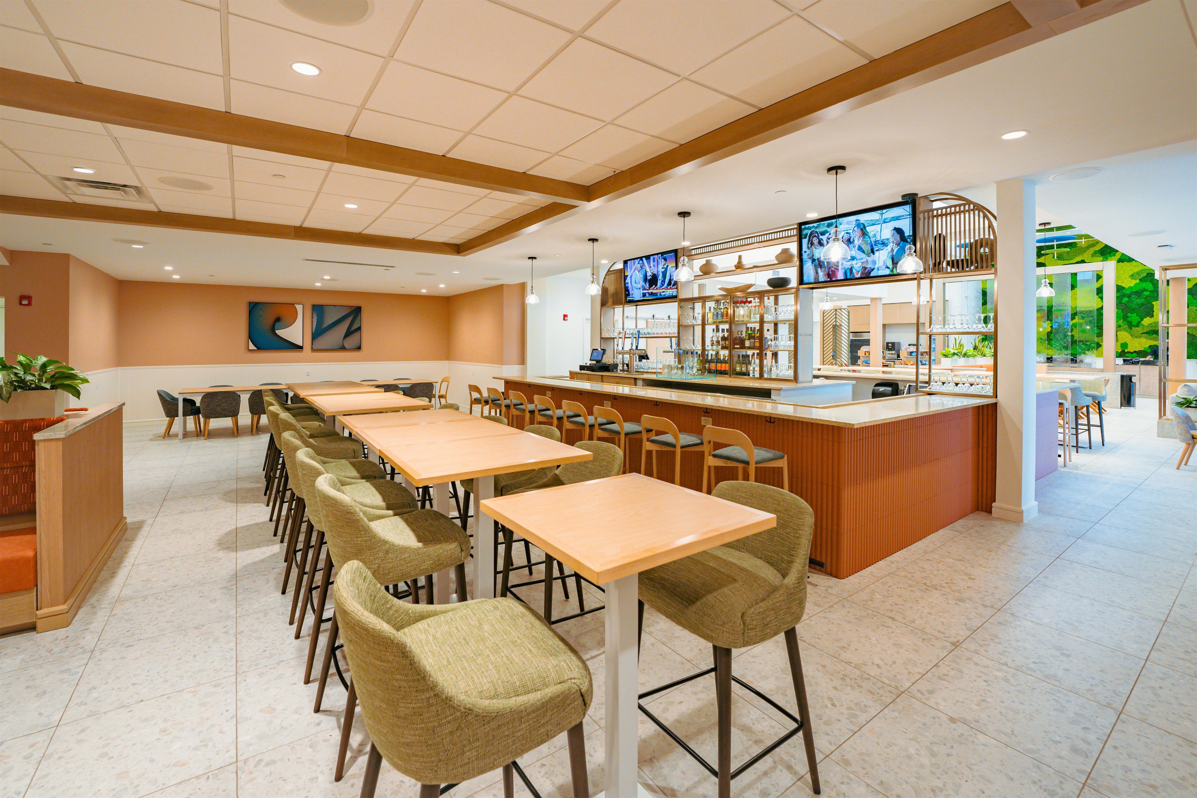 A modern restaurant with a bar area, multiple seating options, and a television screen.
